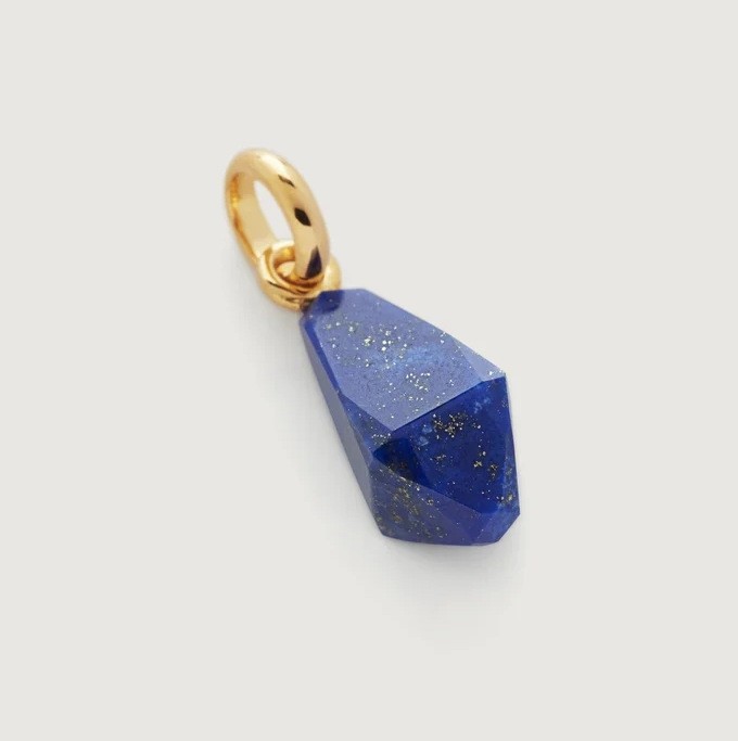 Blue faceted pendant with gold chain on a light gray background