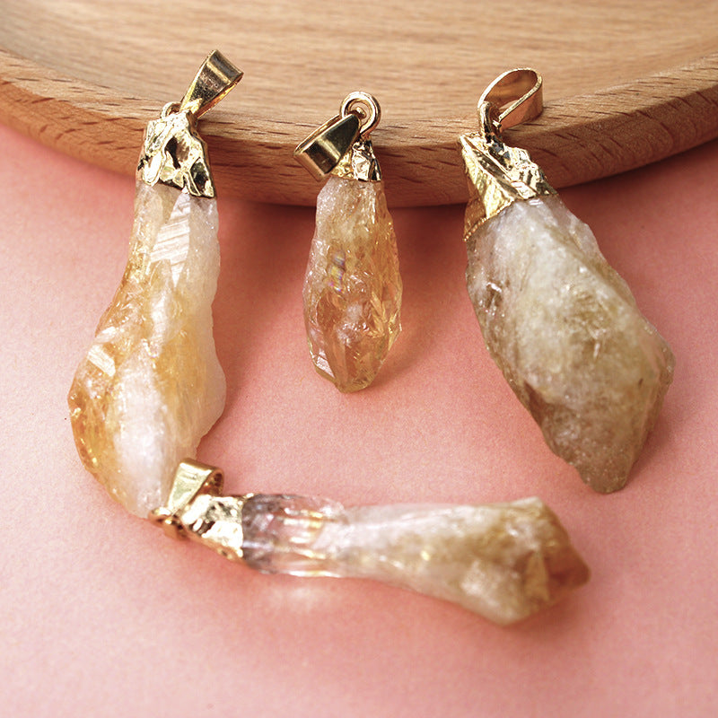 Three stone pendants with gold accents on a wooden block and pink surface