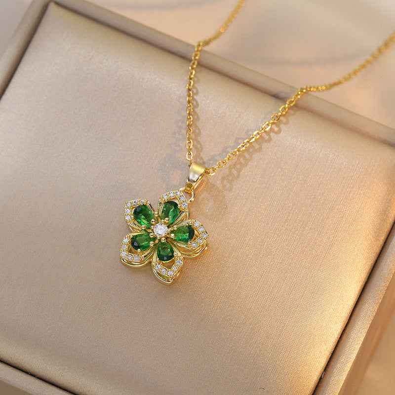 Gold necklace with a green gemstone pendant on a beige surface