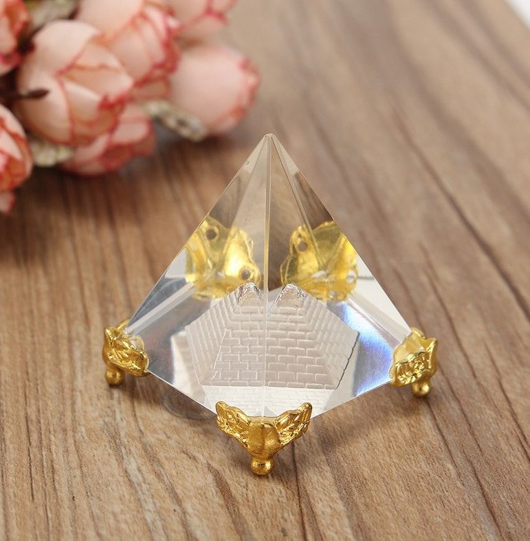 Crystal pyramid with gold accents on a wooden surface