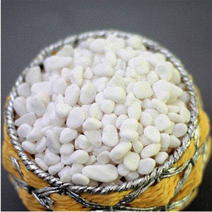 White pebbles in a woven basket with yellow and silver trim on a dark background