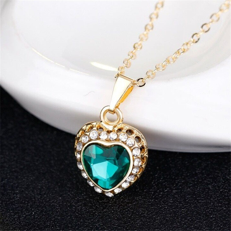 Necklace with a heart-shaped pendant featuring a green gemstone on a dark background