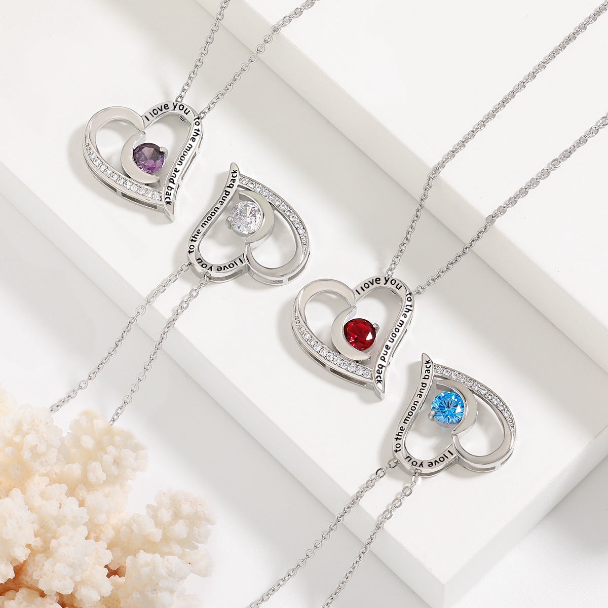 Heart-shaped necklaces with embedded gemstones on a white background