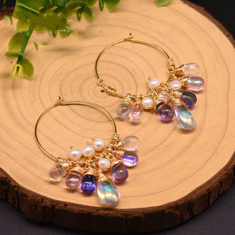 Gold hoop earrings with colorful beads on a wooden surface