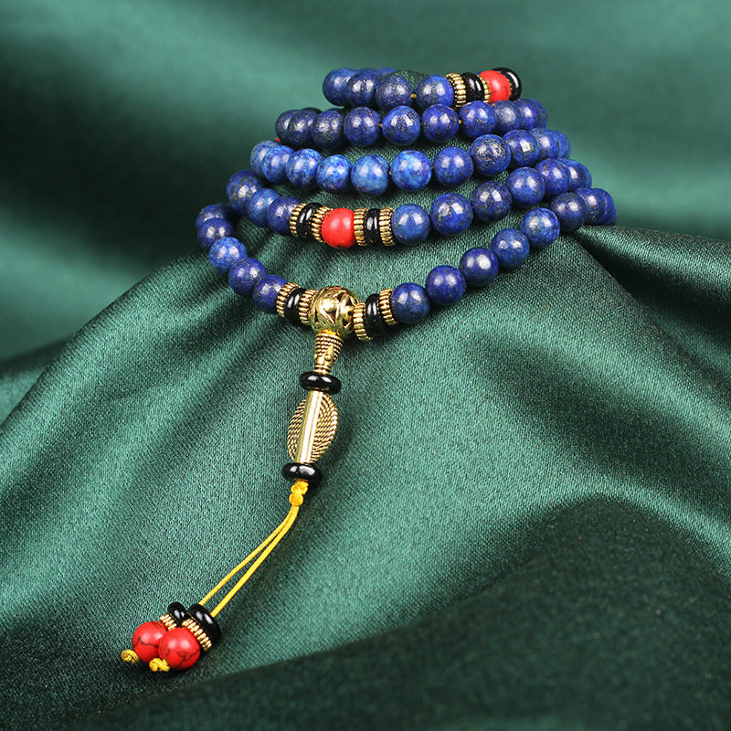 Blue beaded necklace with gold and red accents on a green fabric background