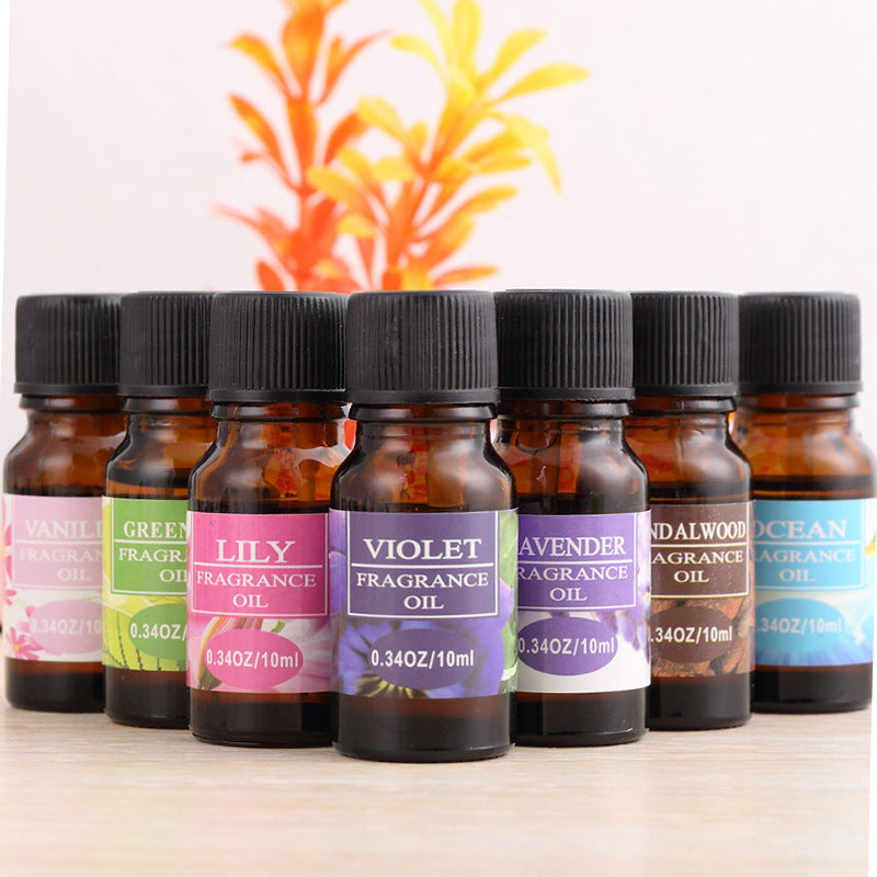 Row of fragrance oil bottles with colorful labels on a wooden surface.
