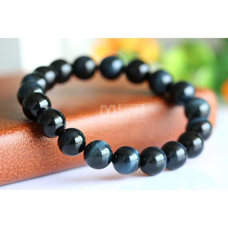 Black beaded bracelet on a wooden surface with a blurred natural background