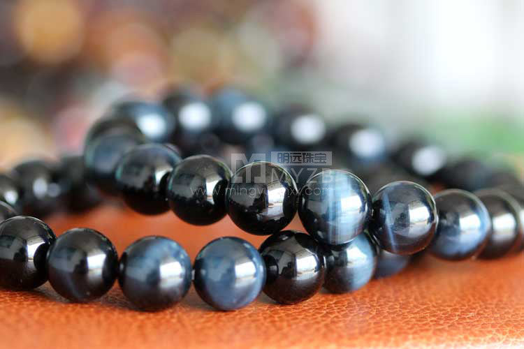 Black beaded bracelet on a textured surface with blurred background