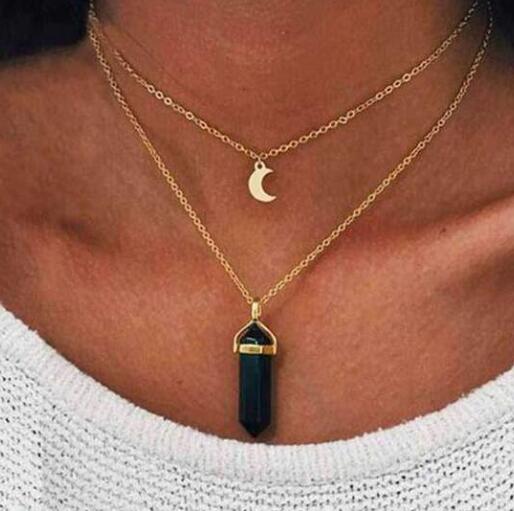 Necklace with a black pendant and gold chain worn by a person