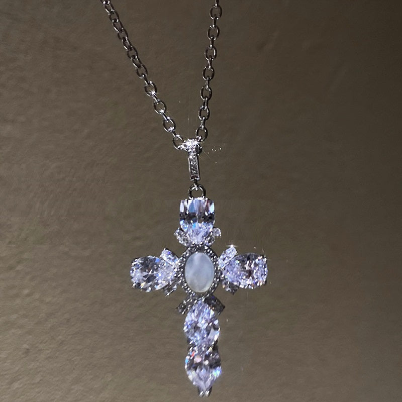 Silver cross pendant necklace with clear stones on a plain background