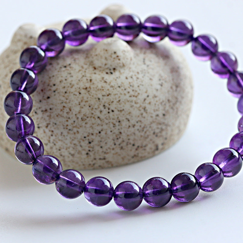 Purple beaded bracelet on a stone surface