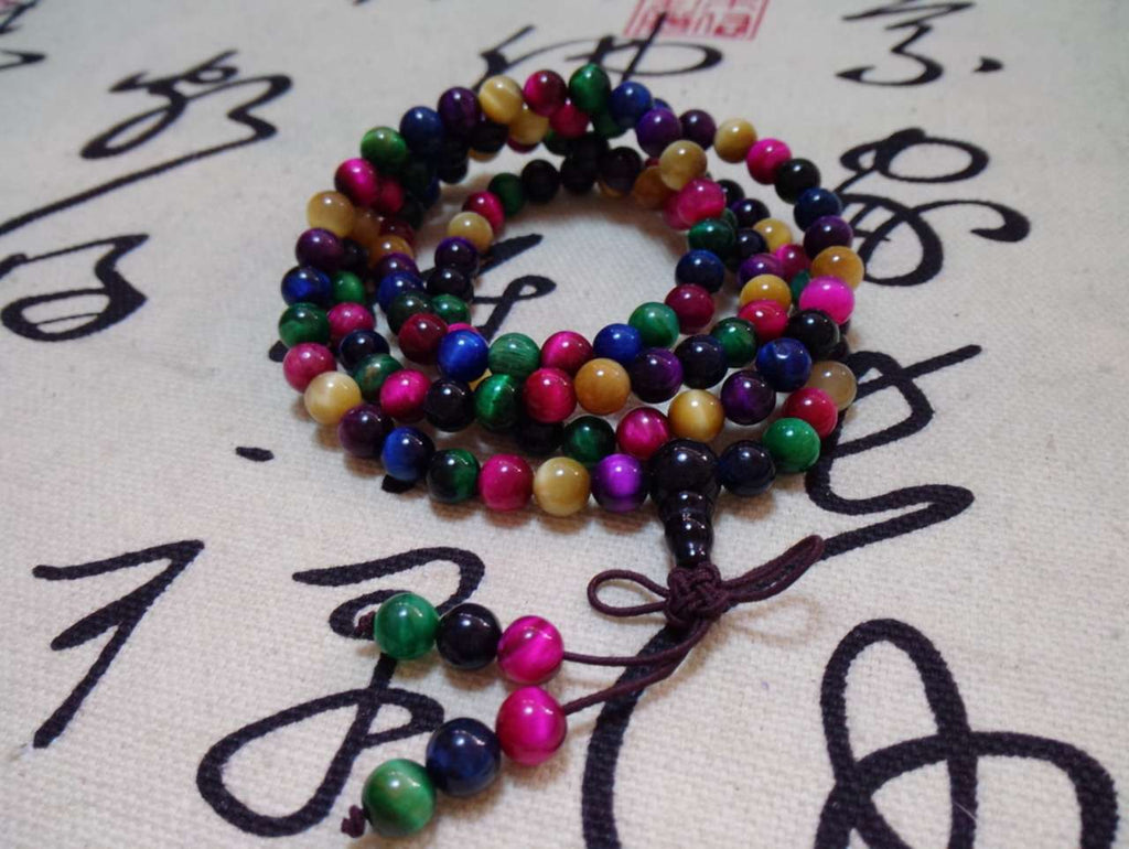 Colorful beaded bracelet on a textured surface with black calligraphy.