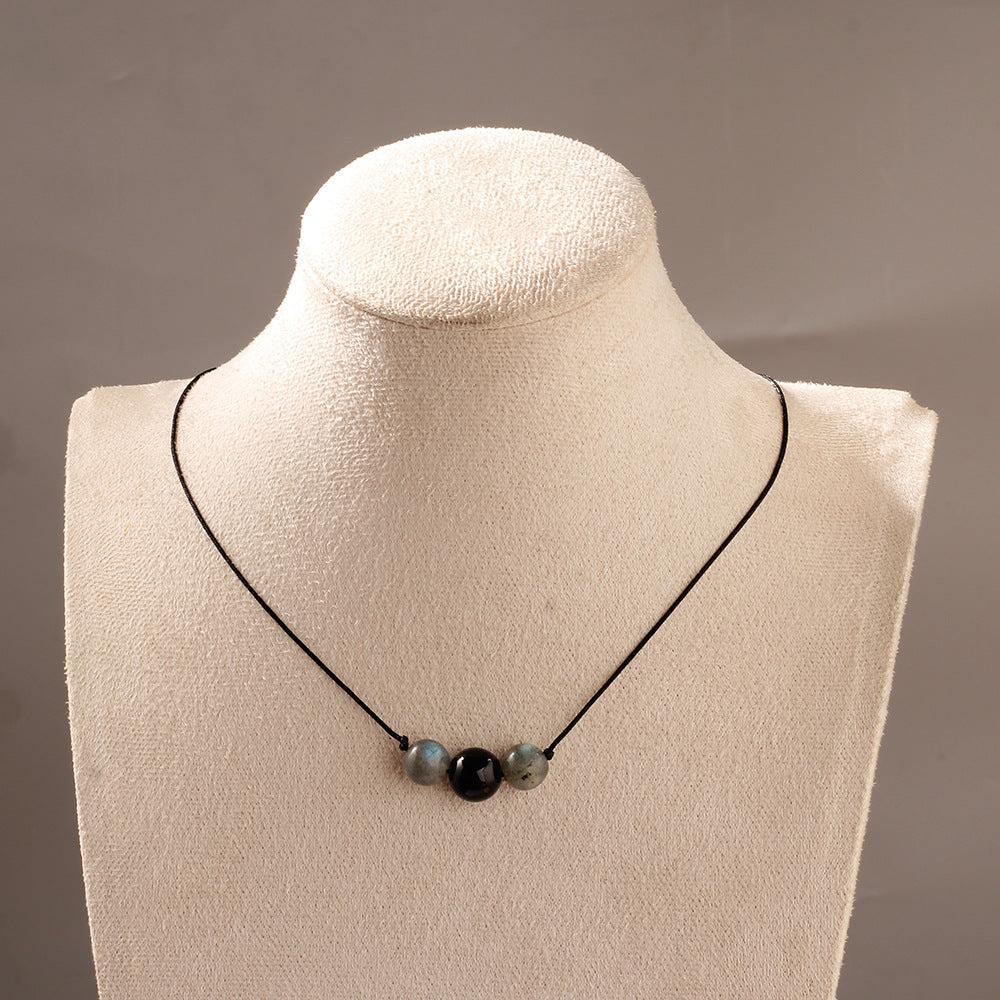 Necklace with three beads on a mannequin bust against a neutral background