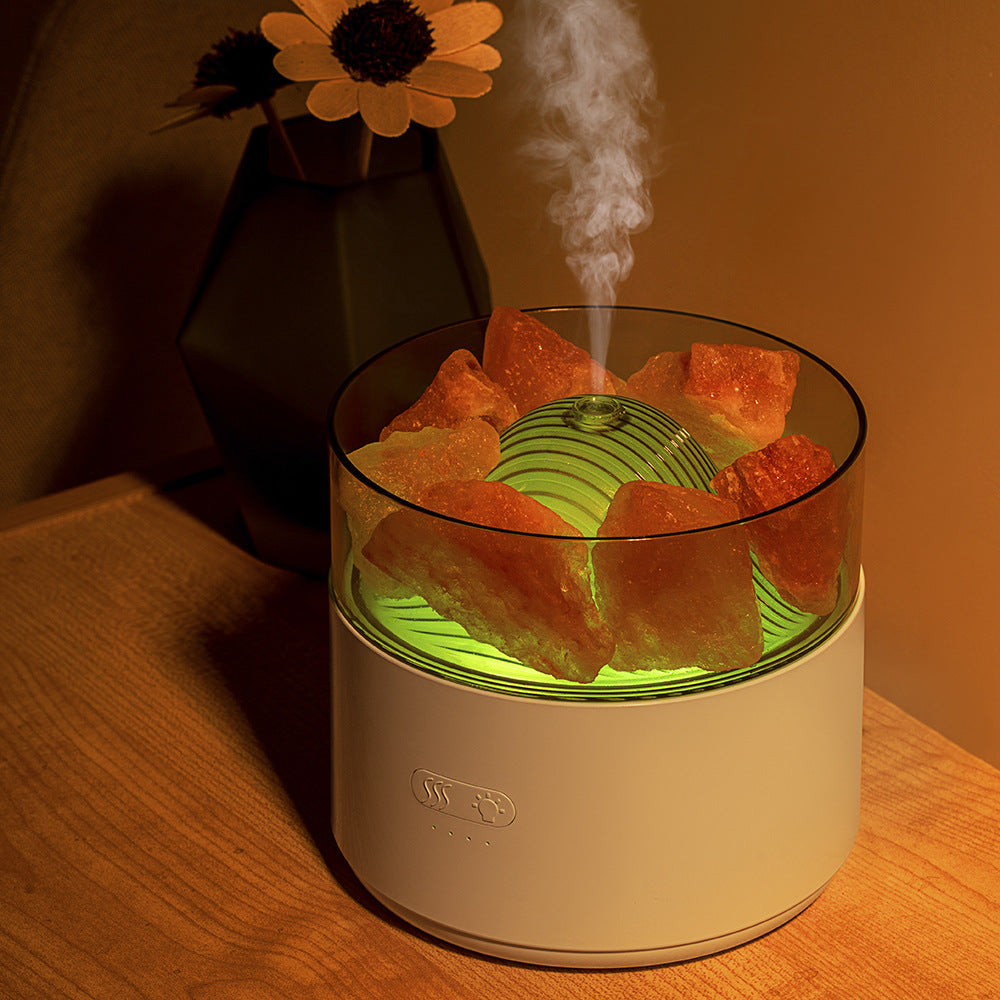 A small humidifier with orange slices on a wooden surface, emitting steam.