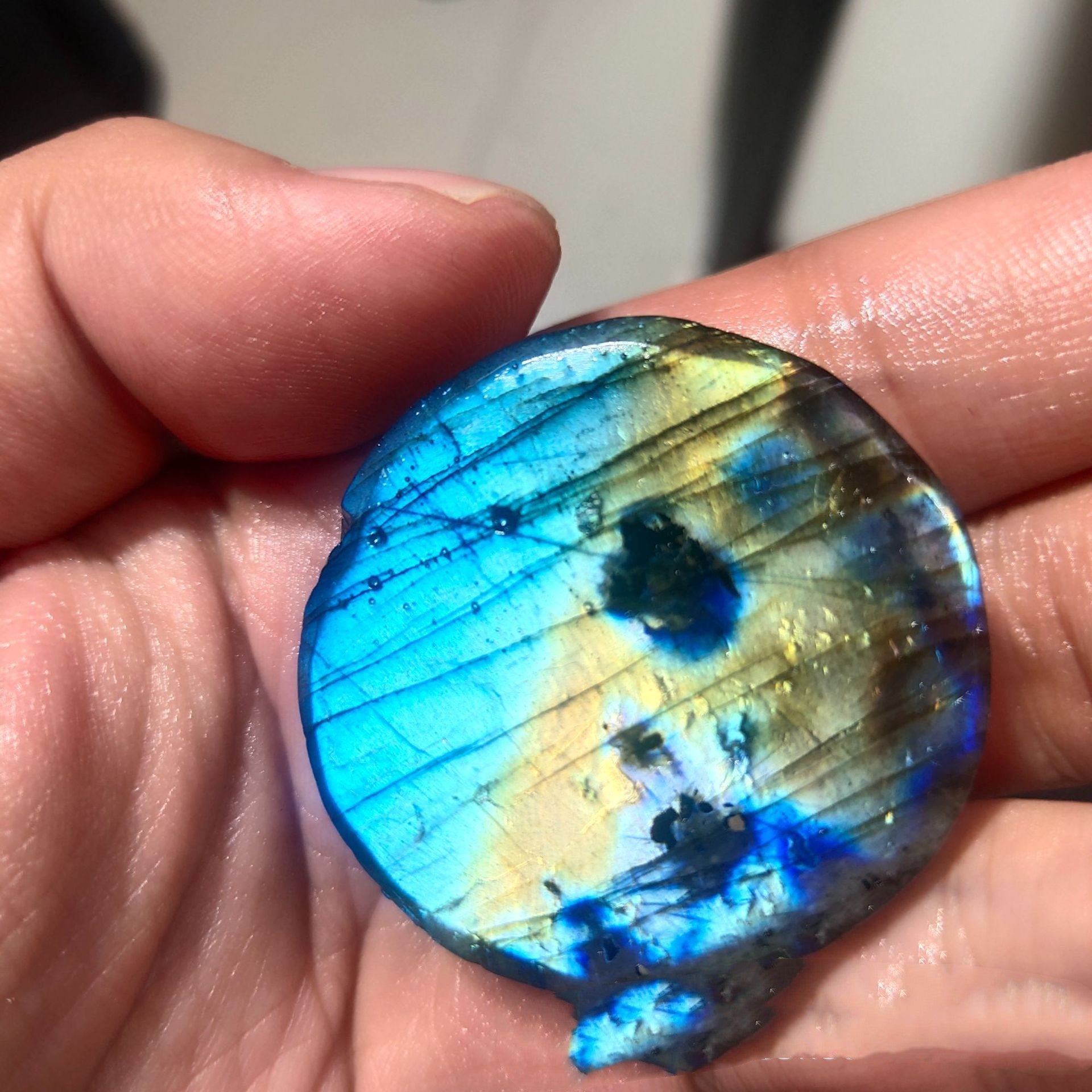Multicolored labradorite stone held between fingers
