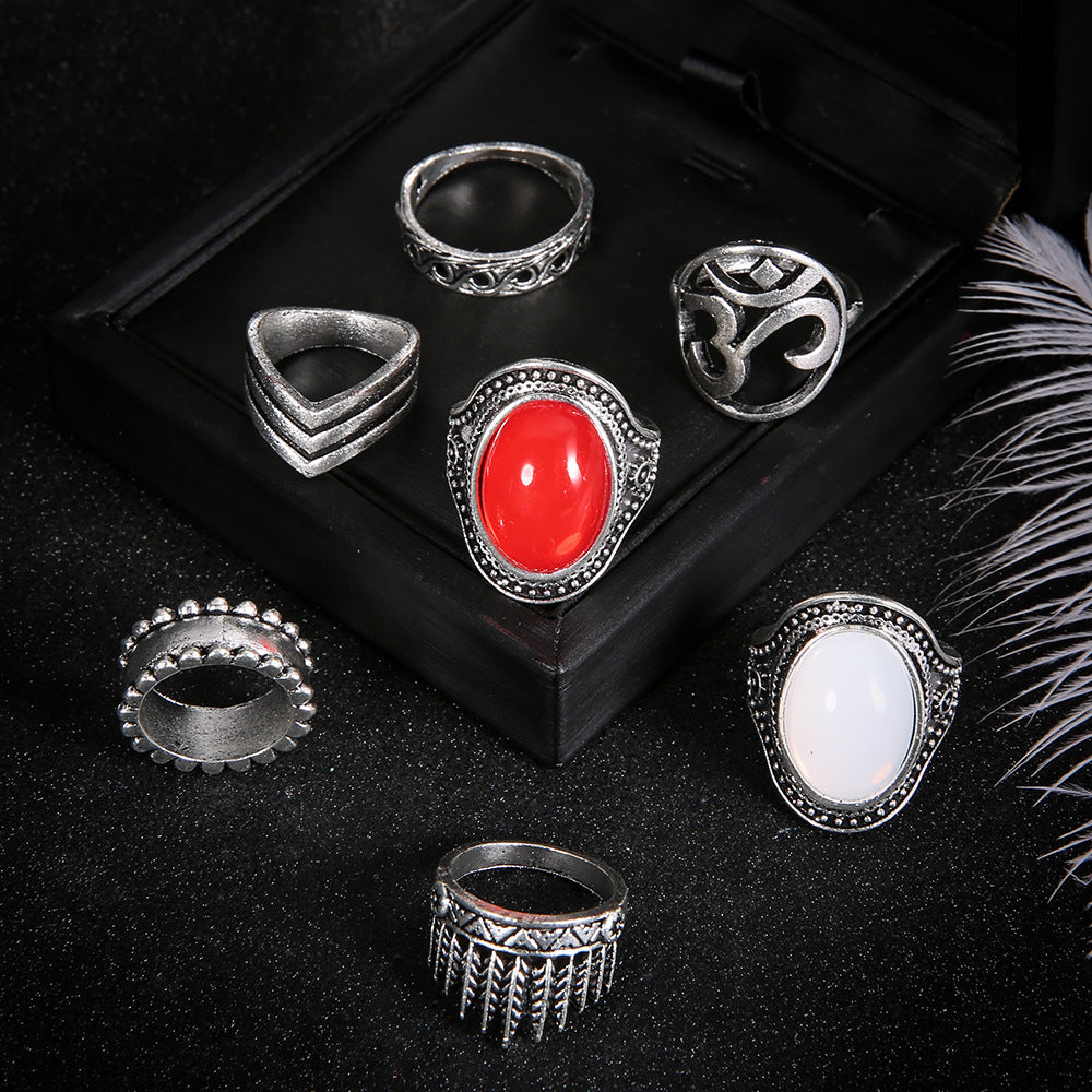 Set of silver rings with red and white stones on a black surface