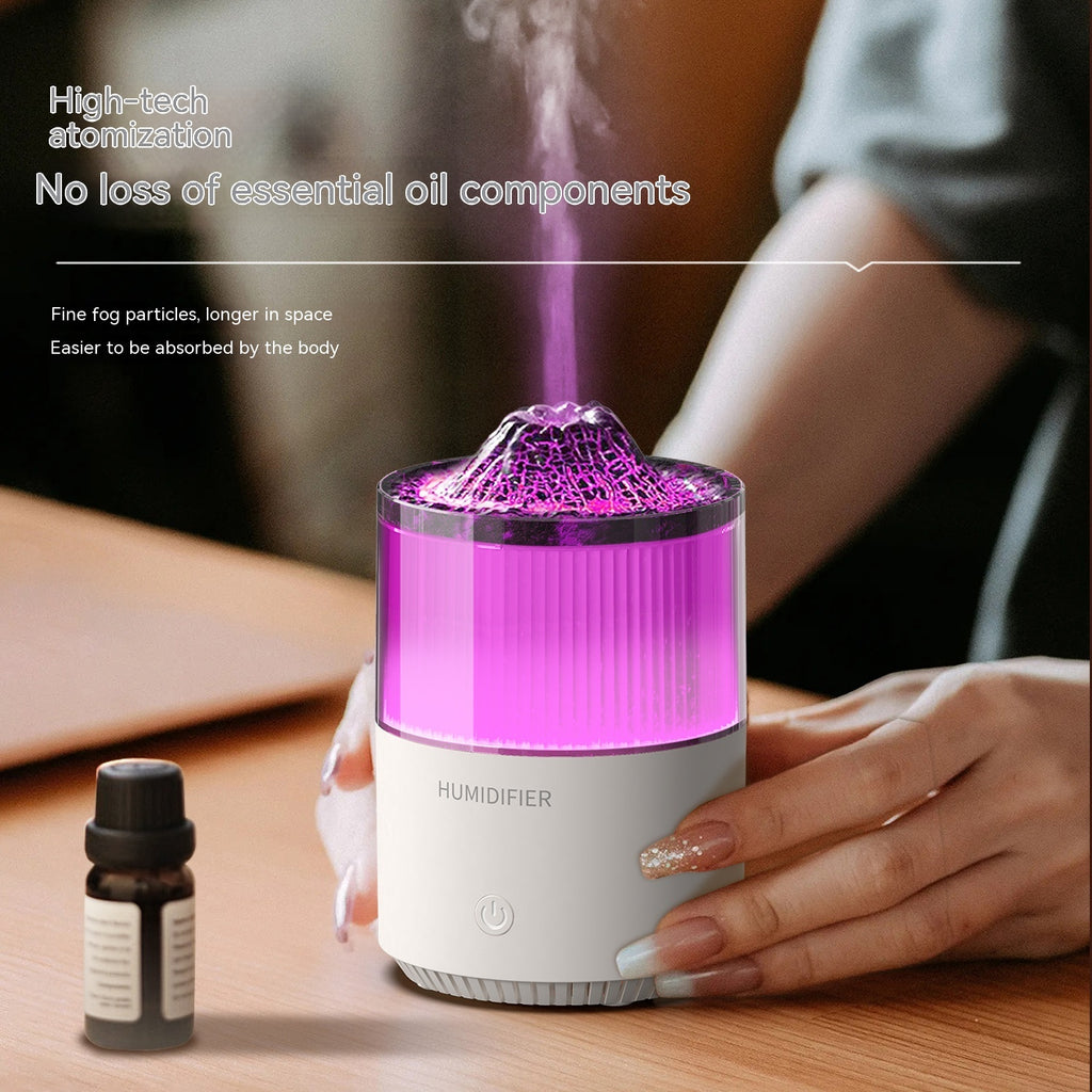 Humidifier with purple light emitting mist, next to an essential oil bottle on a wooden surface.