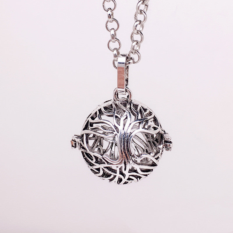 Silver tree of life pendant on a chain against a light pink background