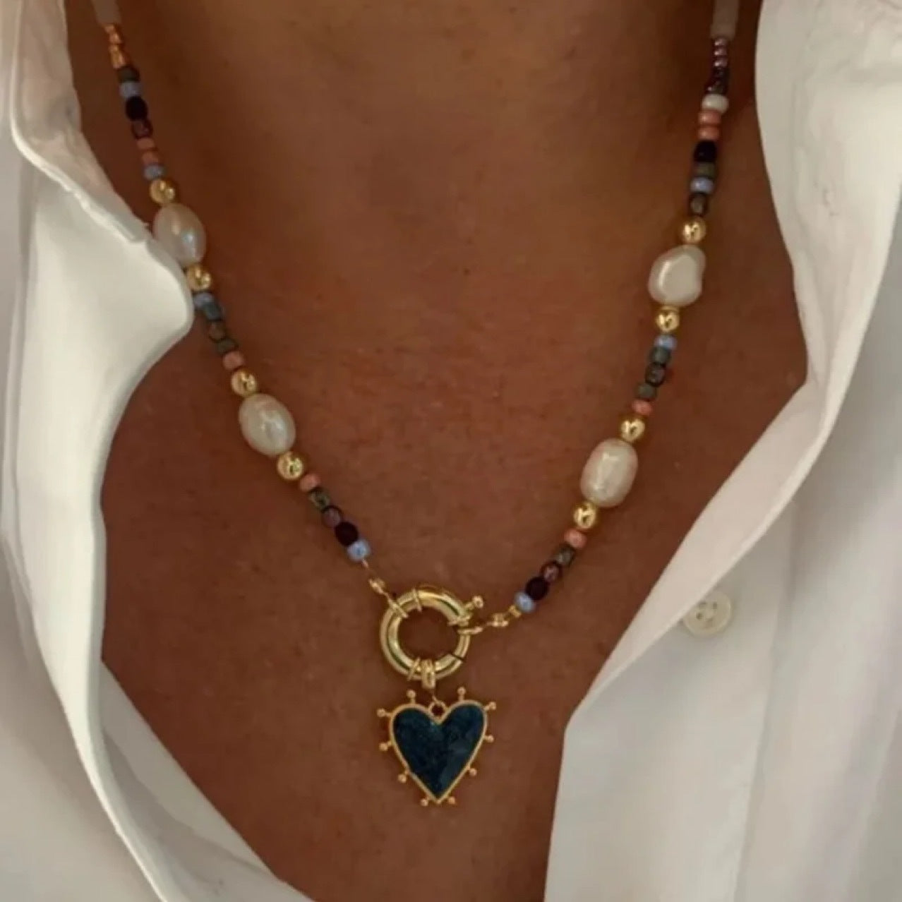Necklace with heart pendant and beaded chain worn by a person