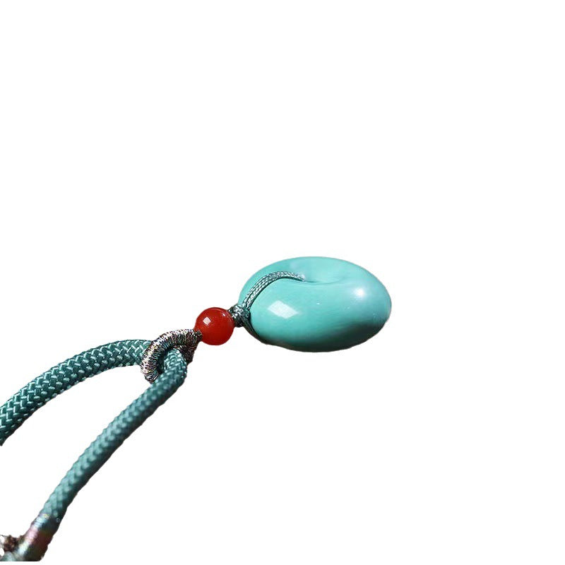Turquoise necklace with a red bead on a white background