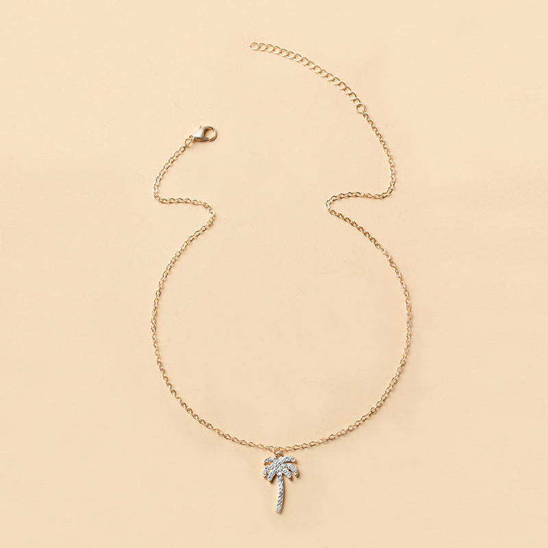 Gold necklace with a palm tree pendant on a beige background