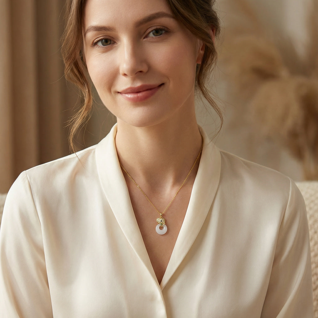 Woman wearing a cream-colored blouse and gold necklace with a pendant.