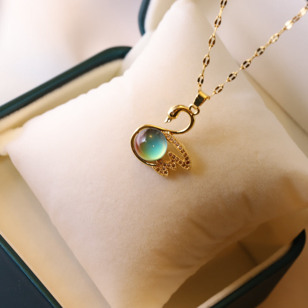 Gold necklace with a green gemstone pendant on a white cushion