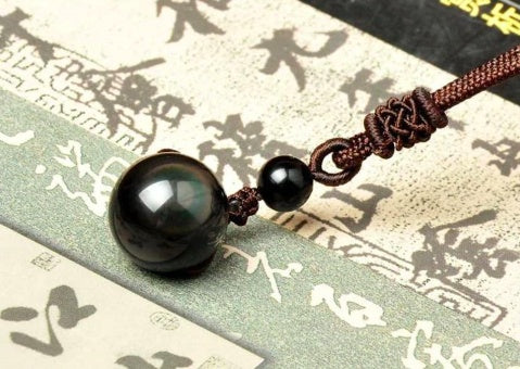 Black beaded necklace on a textured surface with Chinese characters