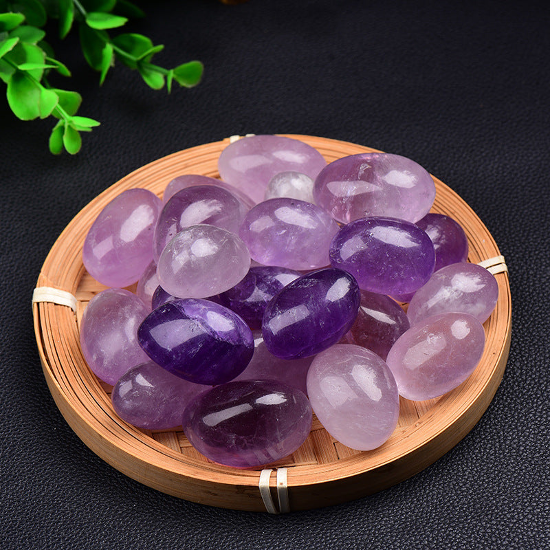 Purple and pink gemstones on a round wooden tray with a dark background