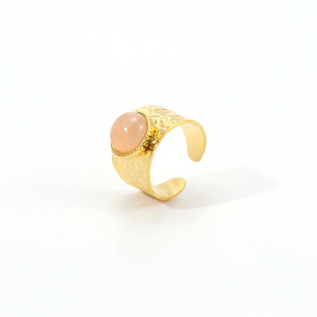 Gold ring with a pink stone on a white background