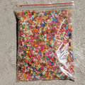 Bag of colorful small beads on a concrete surface