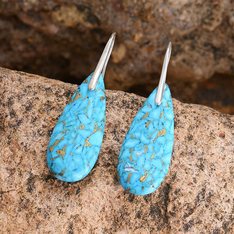 Turquoise earrings with silver hooks on a stone surface