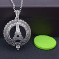 Silver pendant with Eiffel Tower design on a dark surface with a green round object.