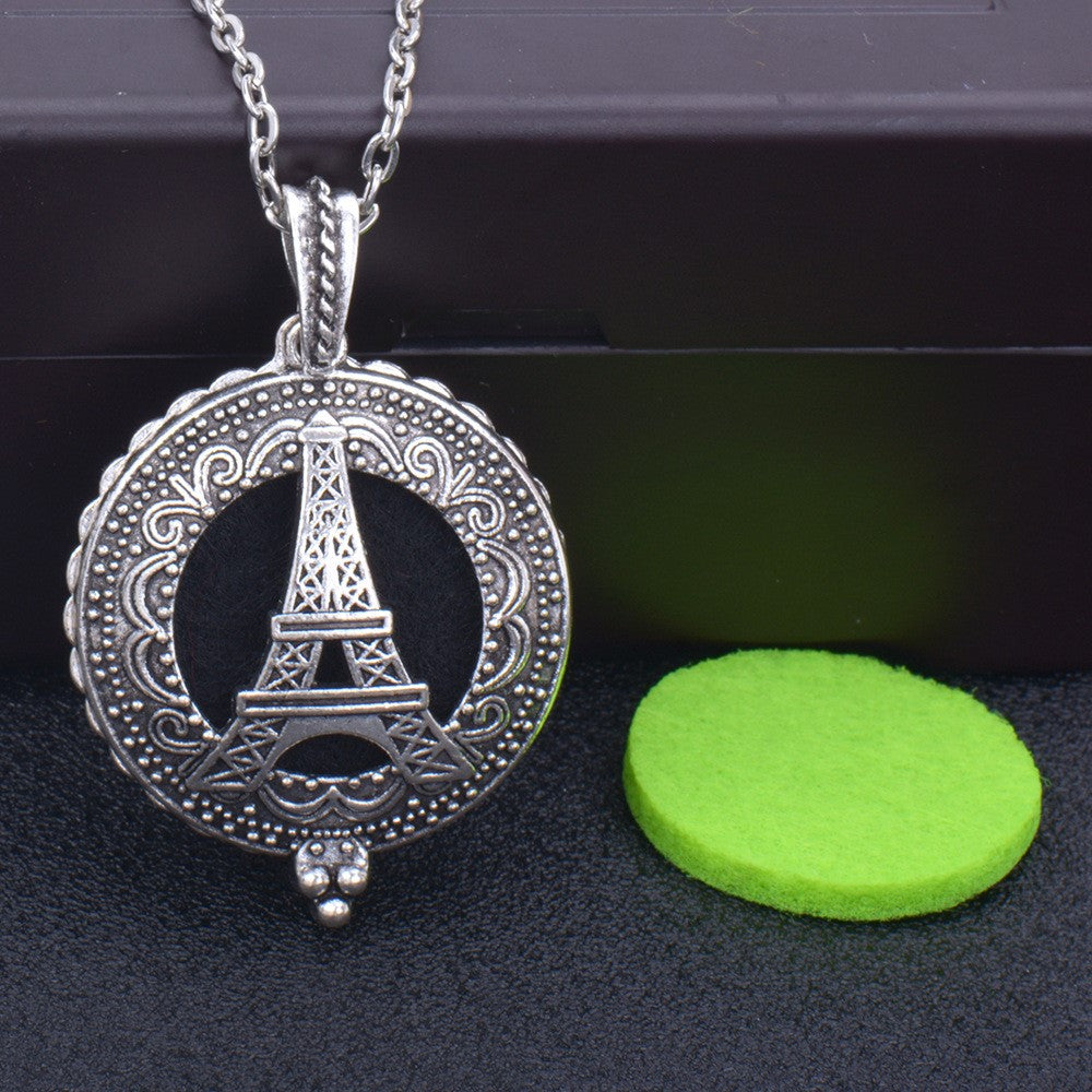 Silver pendant with Eiffel Tower design on a dark surface with a green round object.