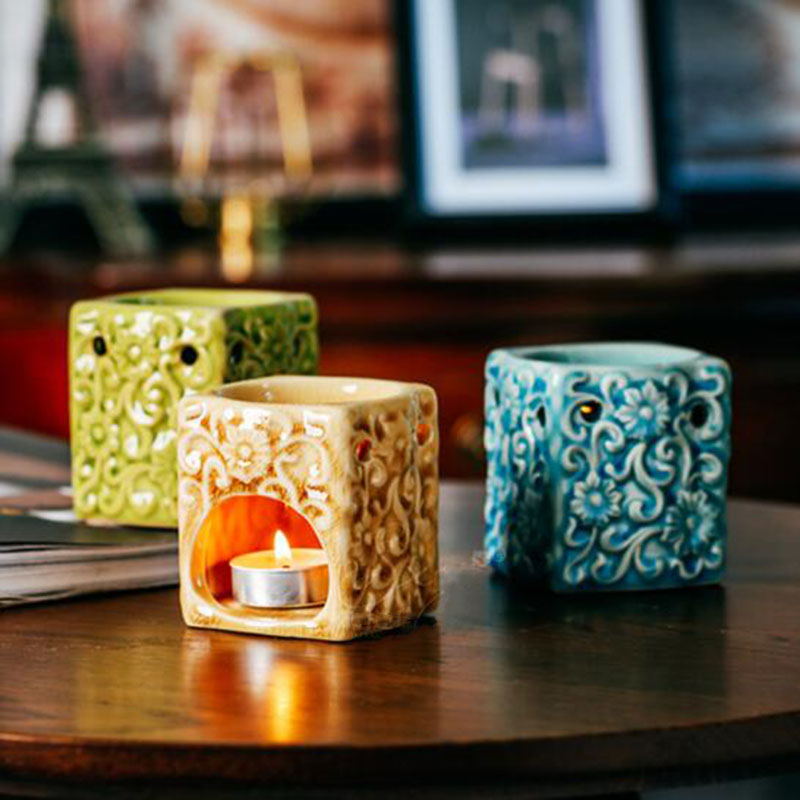 Three decorative ceramic warmers on a wooden surface with a blurred indoor background.