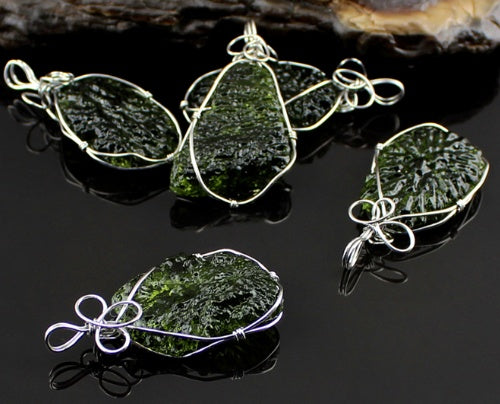 Set of green stone pendants with silver wire wrapping on a dark surface