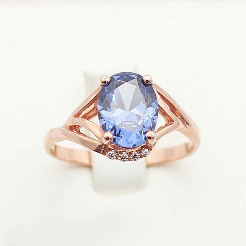 Rose gold ring with a blue gemstone on a white background