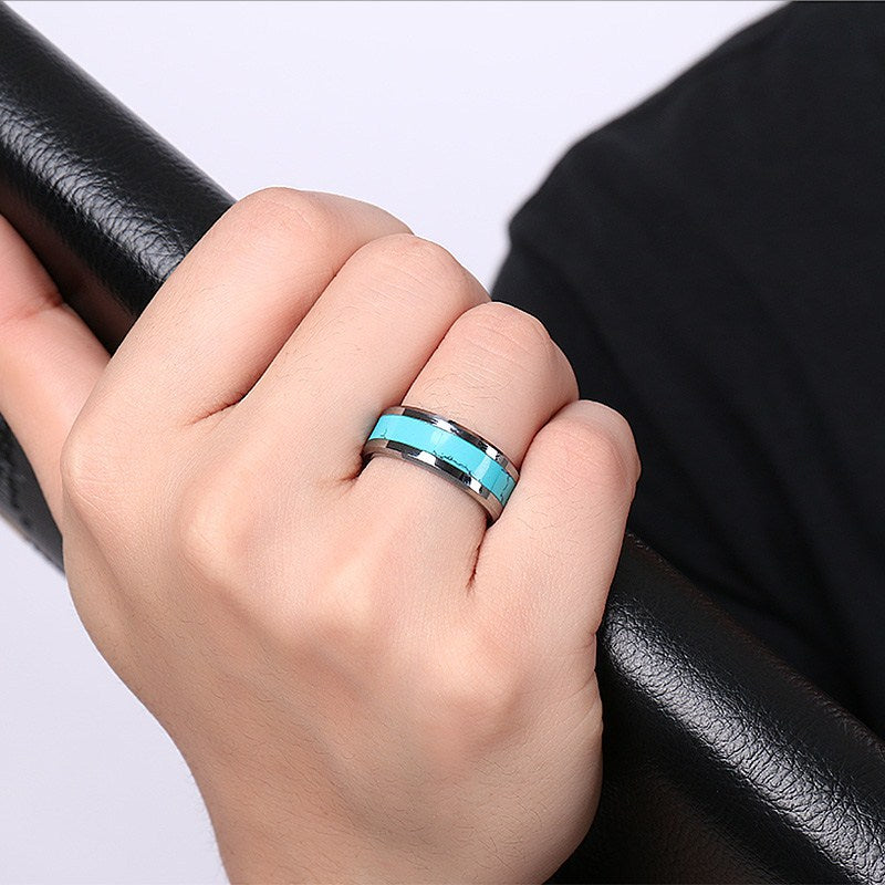 Hand wearing a turquoise ring on a black leather surface