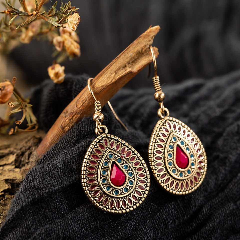 Ornate earrings with red gemstones on a dark fabric background