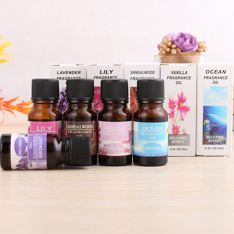 Set of fragrance oil bottles with colorful labels on a wooden surface.