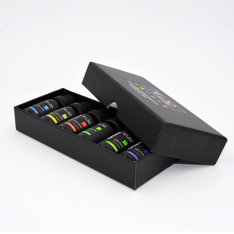 Set of small bottles with colorful labels in an open black box on a white background