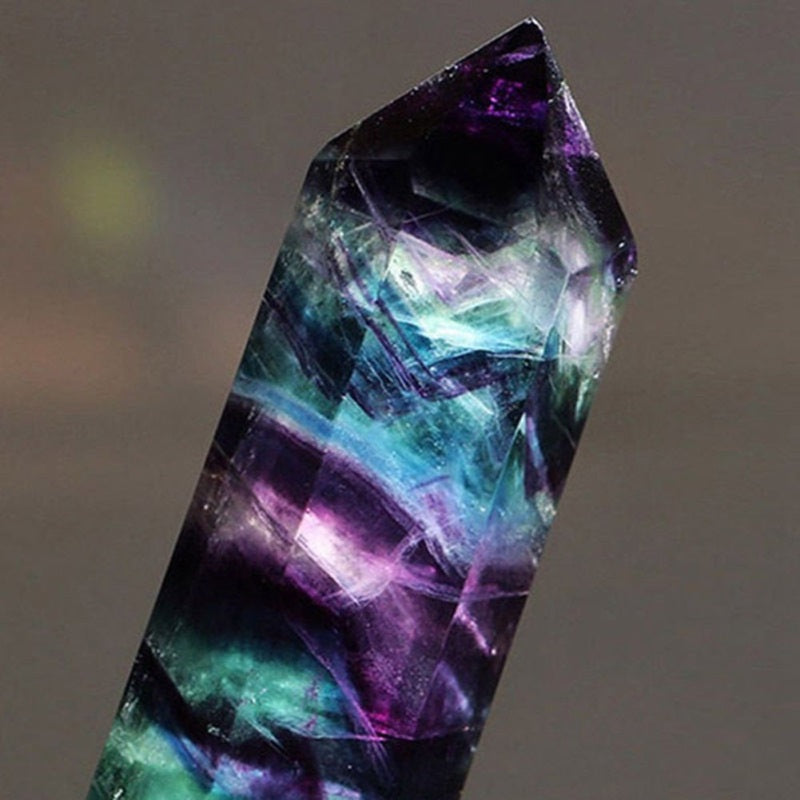 Multicolored crystal with purple and green hues on a gray background
