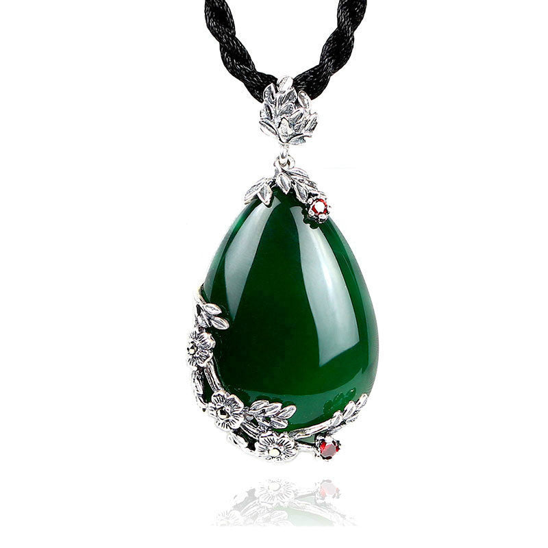 Green teardrop pendant with silver and black cord on a white background