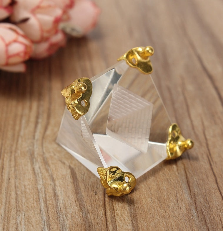 Gold earrings on a clear stand with a wooden background