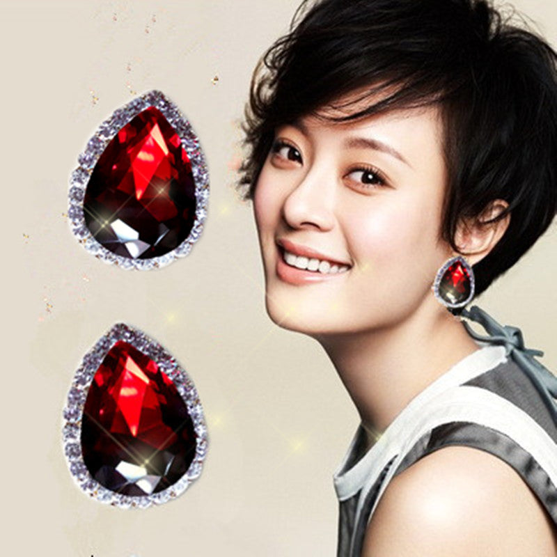 Woman wearing red teardrop earrings with a beige background
