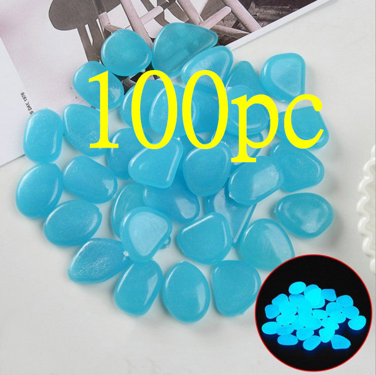 100 blue glow-in-the-dark pebbles on a white surface with an inset showing their glow.