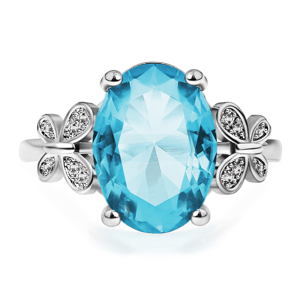 Ring with a blue gemstone and silver floral accents on a white background