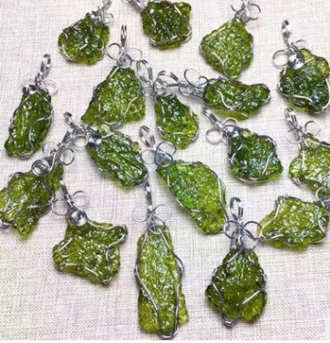 Green stone pendants on silver chains arranged on a textured white surface