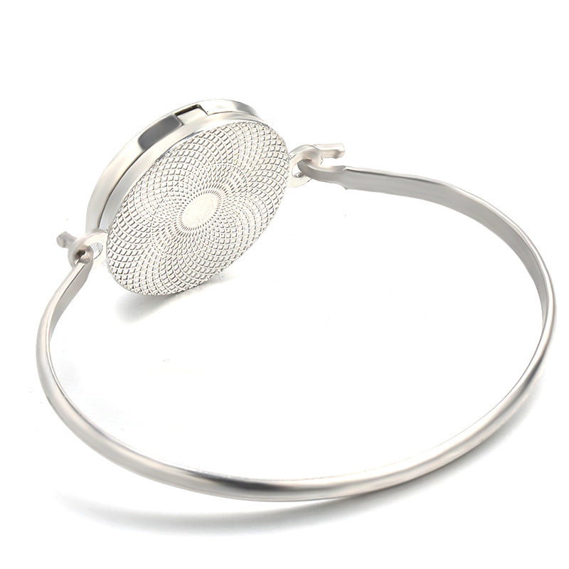 Silver bangle with textured round element on a white background