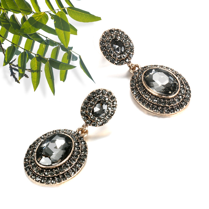 Pair of ornate earrings with dark gemstones on a white background